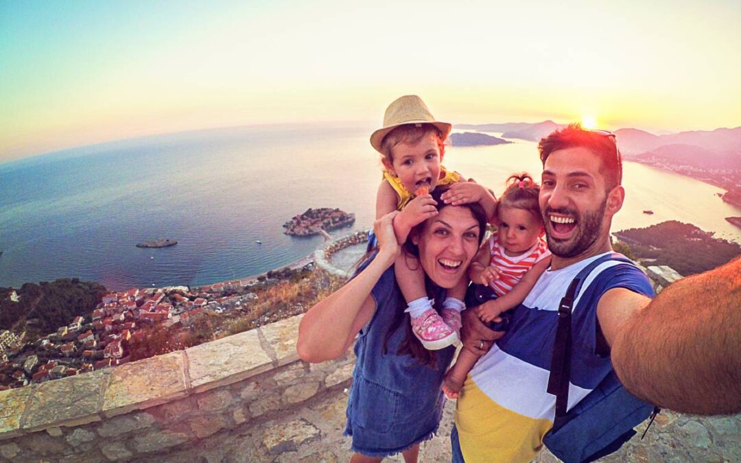 Familia de cuatro selfie mientras está de vacaciones con vista al océano.