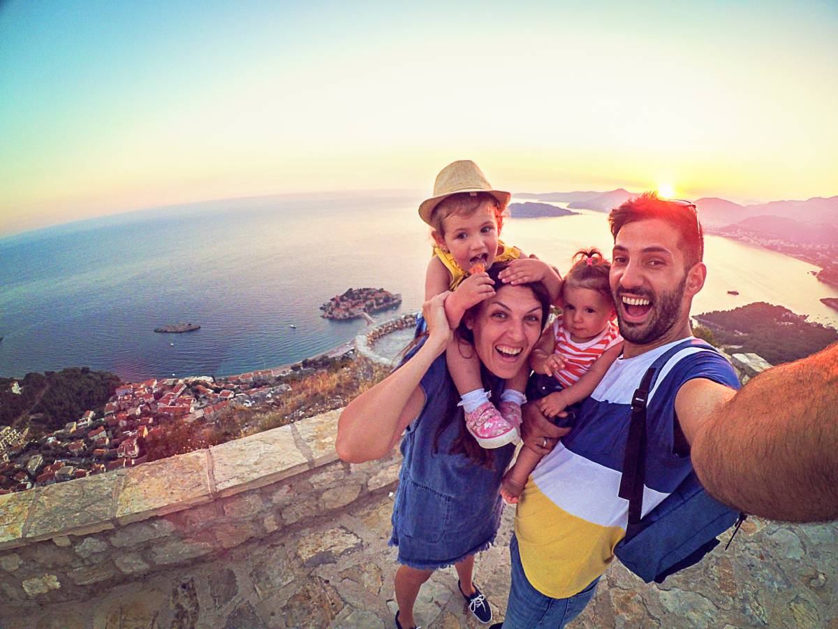 Family of four selfie while on vacation overlooking the ocean.