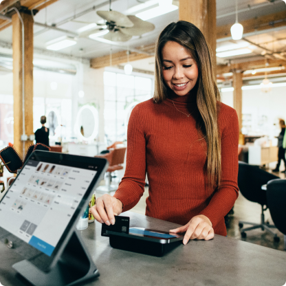 A young woman swiping her credit card at a small business.