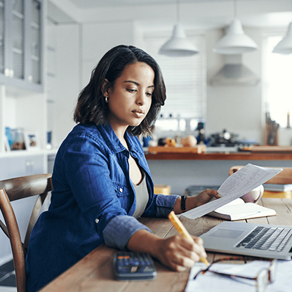 Business woman working at home kitchen table on financials
