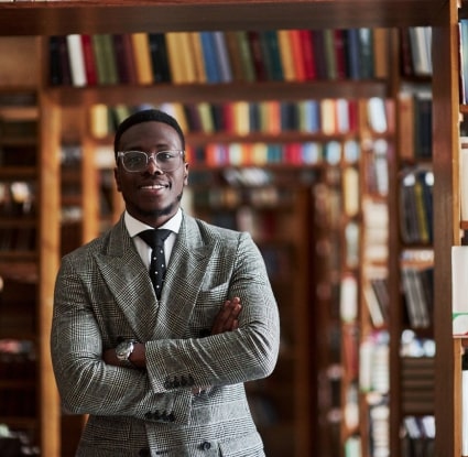 An intellectual property attorney standing in a law library with his arms crossed and smiling.