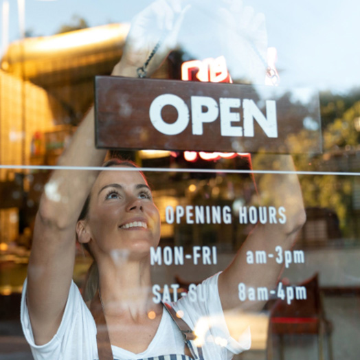 Business owner placing an open sign on the door of her new business.