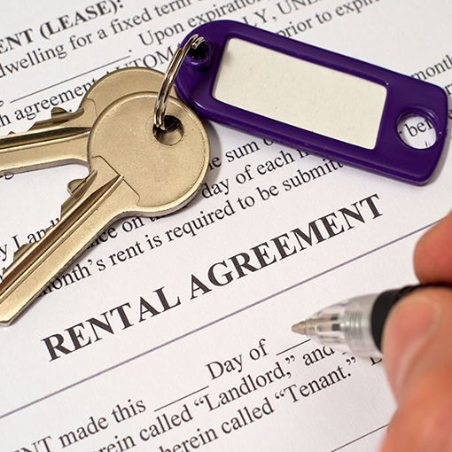 Person filling out a Rental Agreement with keys laying nearby