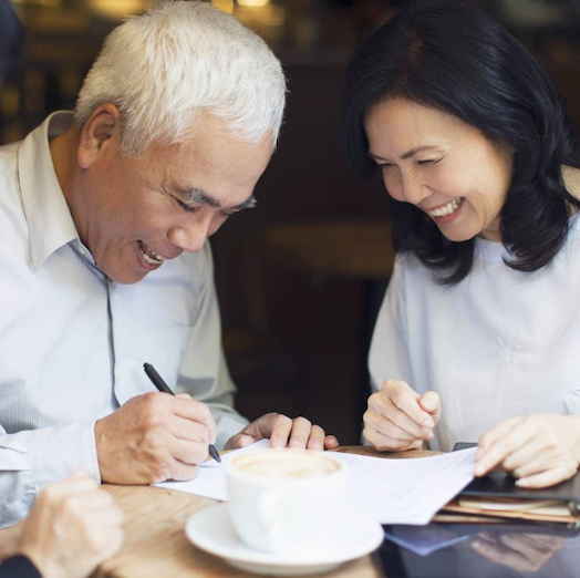 Un hombre firma un poder notarial ante la mirada de su mujer