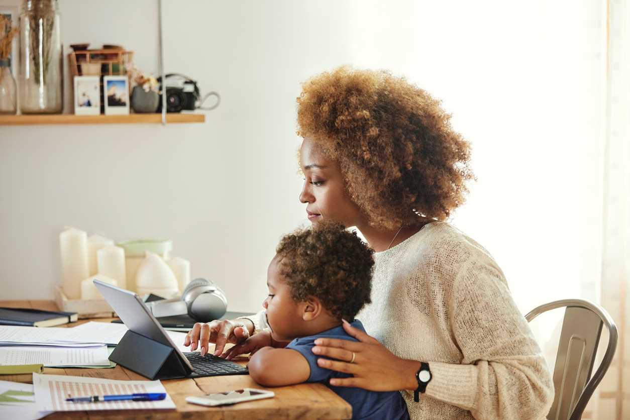 Madre con un niño pequeño en su regazo trabajando en una tableta