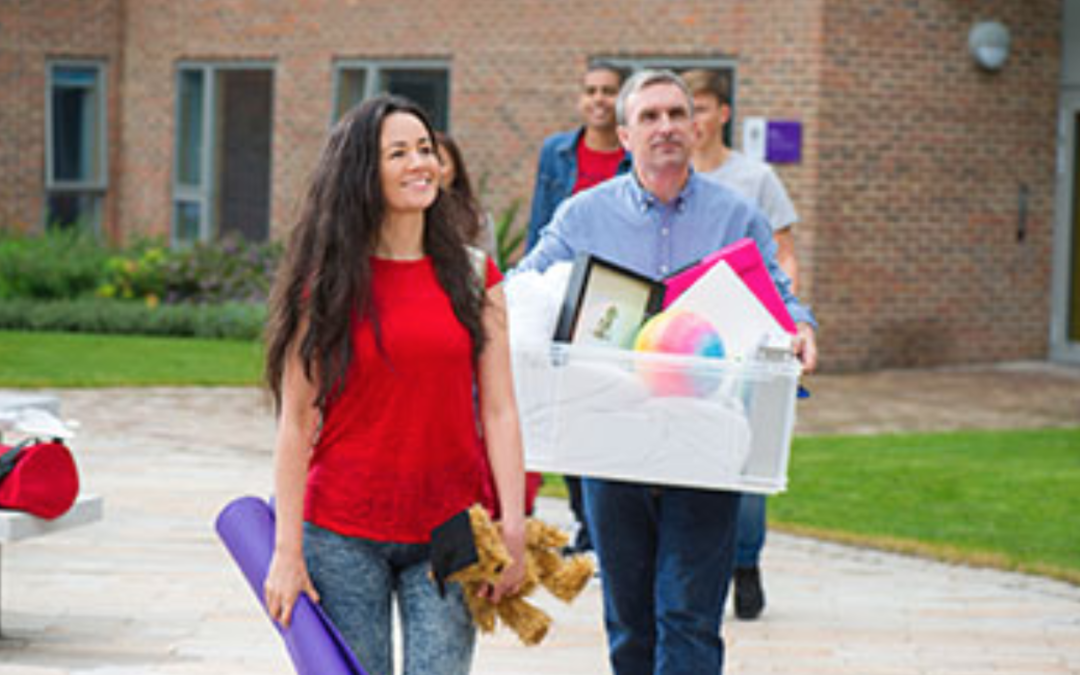 Estudiante universitaria junto a un hombre que lleva una caja con sus pertenencias