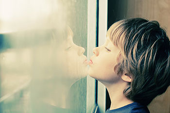 Little boy with special needs looking out a window