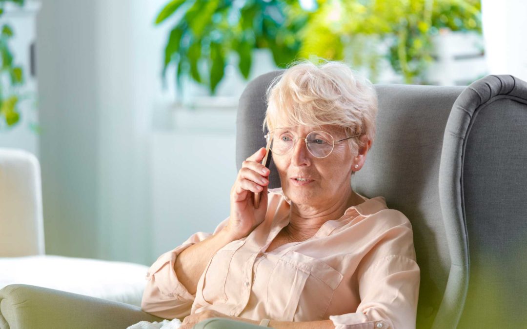 Anciana sentada en una silla cómoda y hablando por un teléfono celular
