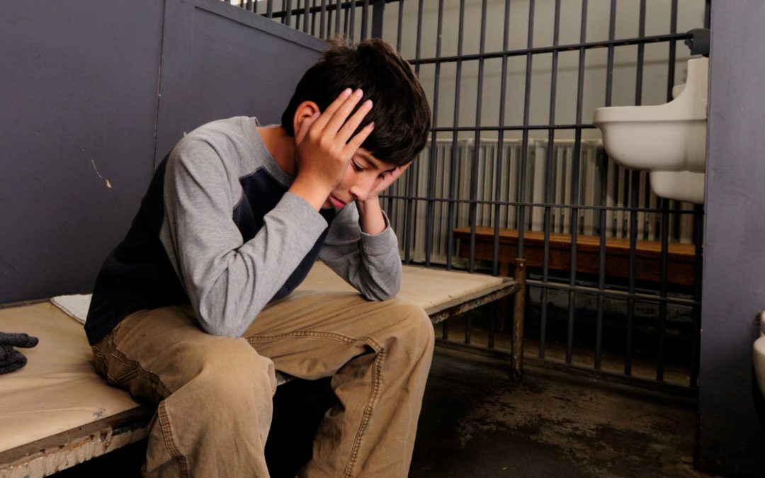 Adolescente sentado en una celda de la cárcel