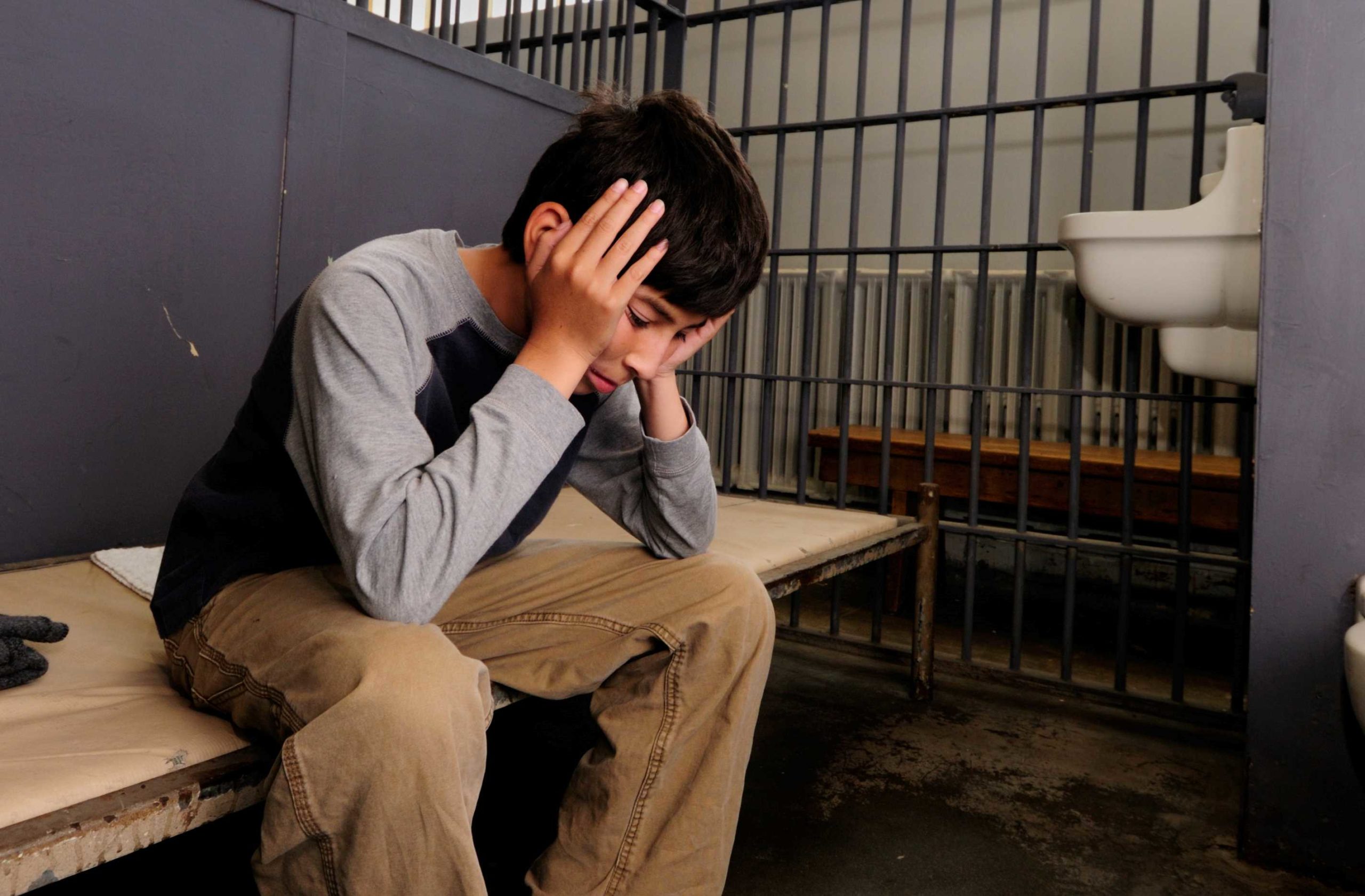 Teenager sitting in a jail cell
