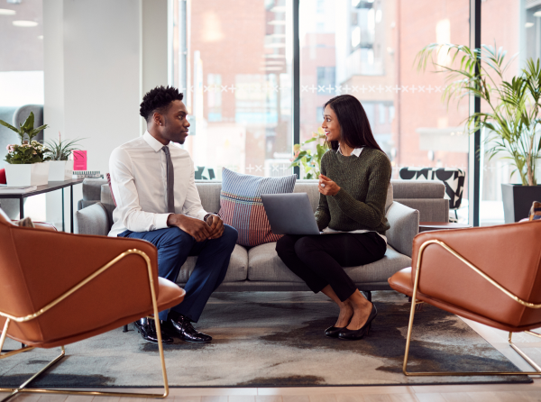 Female business owner talking with employee while sitting on a couch