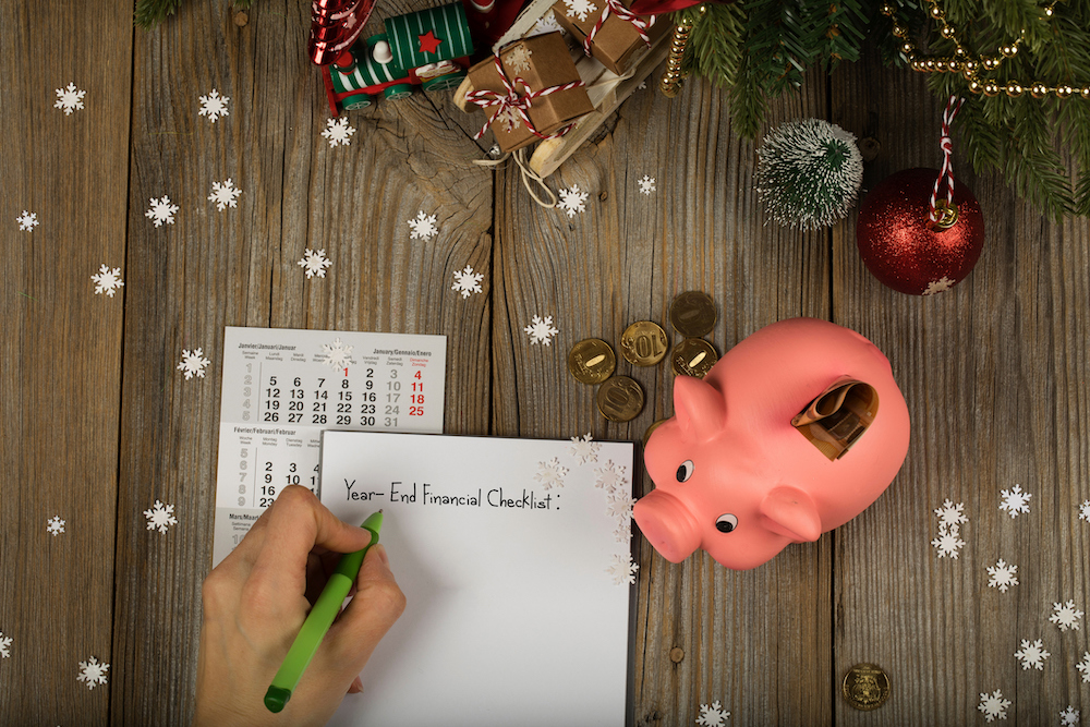 Hoja de papel con la lista de verificación financiera de fin de año escrita en ella y una alcancía rosa con antecedentes de año nuevo