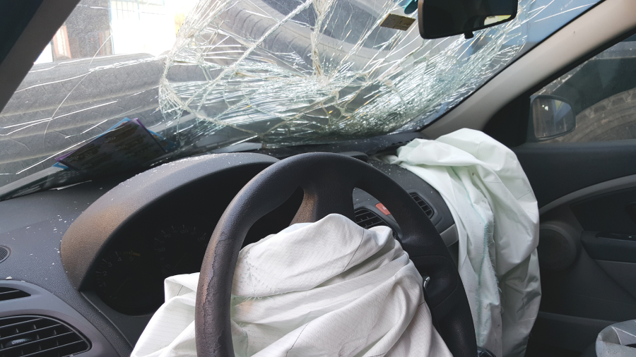 Inside of car after an accident showing broken windshield & deflated airbags