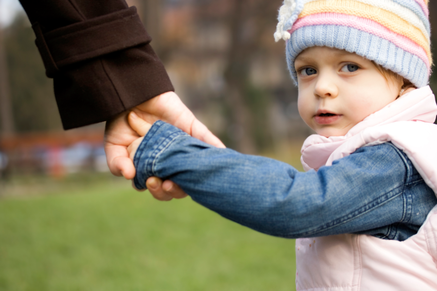 Small child holding hands with a caregiver