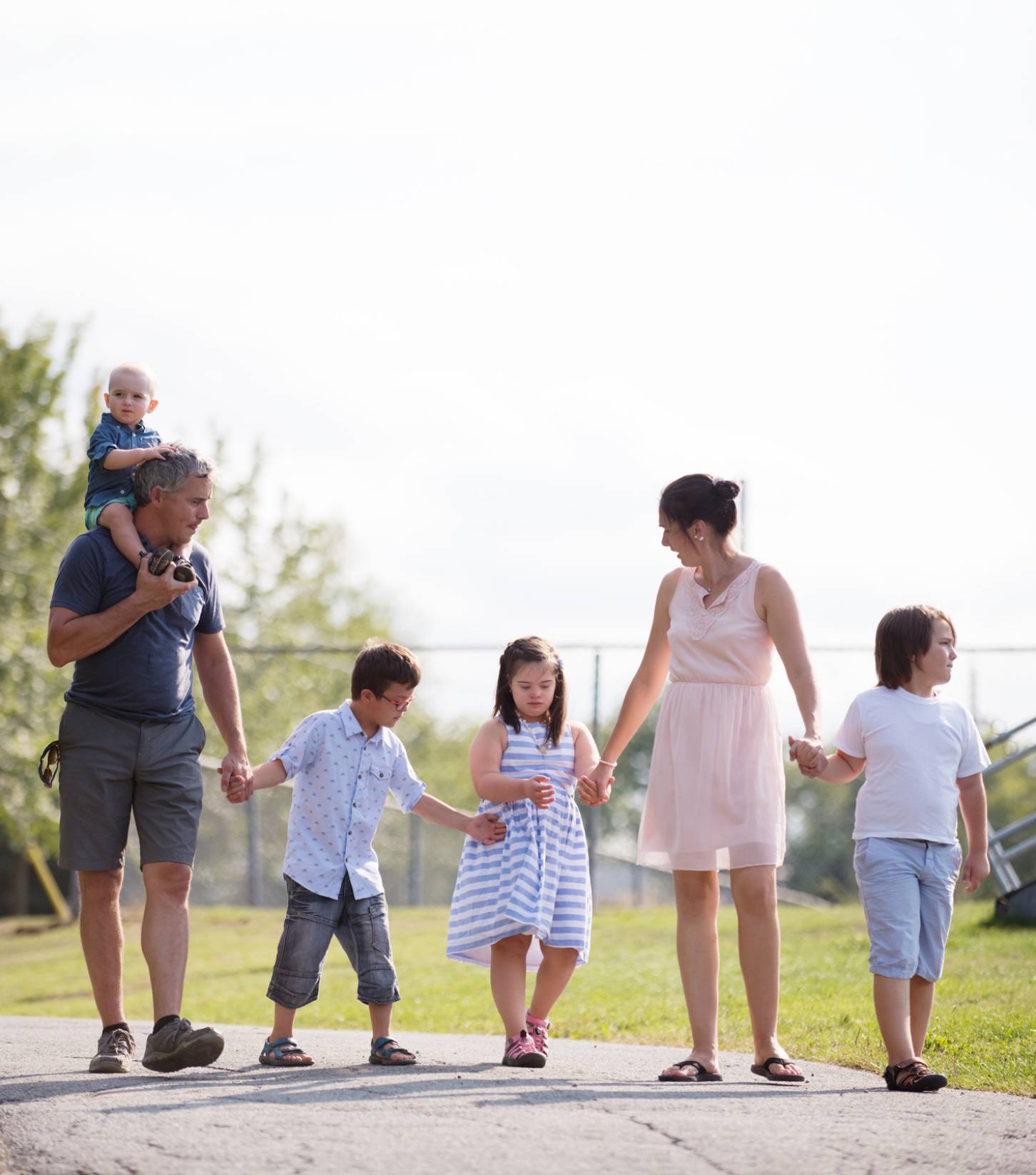 Couple with 4 small children taking a walk & all holding hands