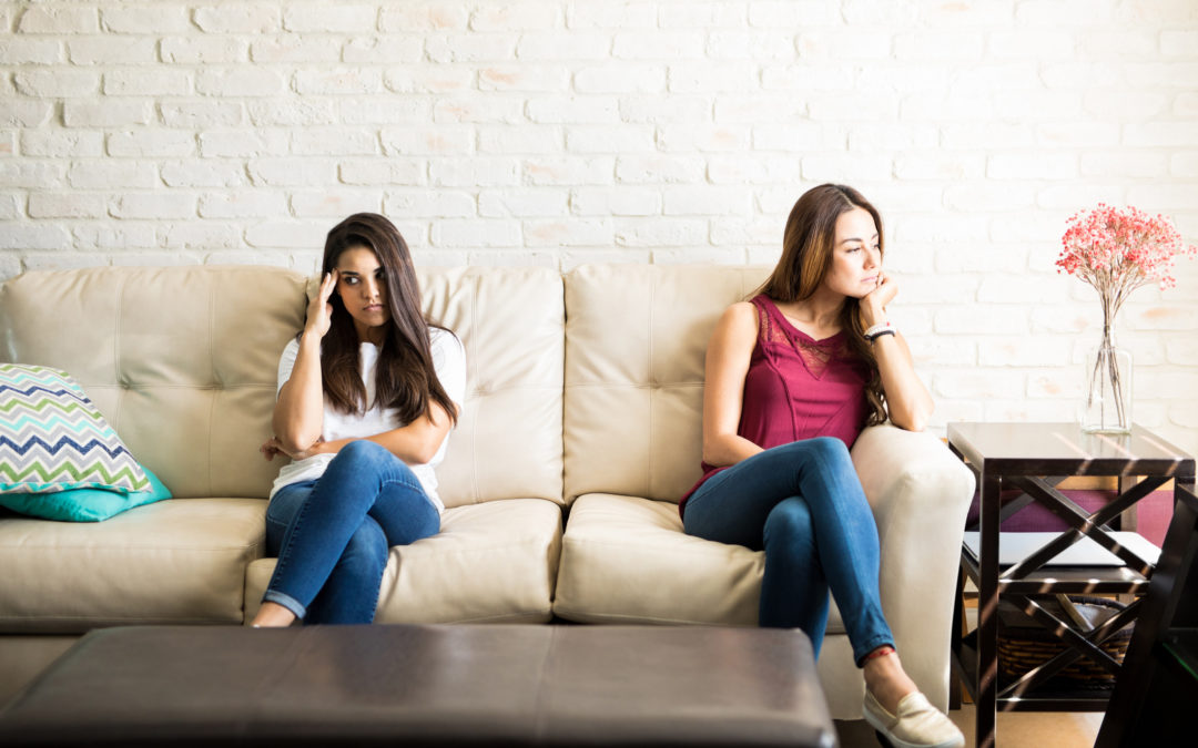 Unhappy roommates sitting on a couch but not talking