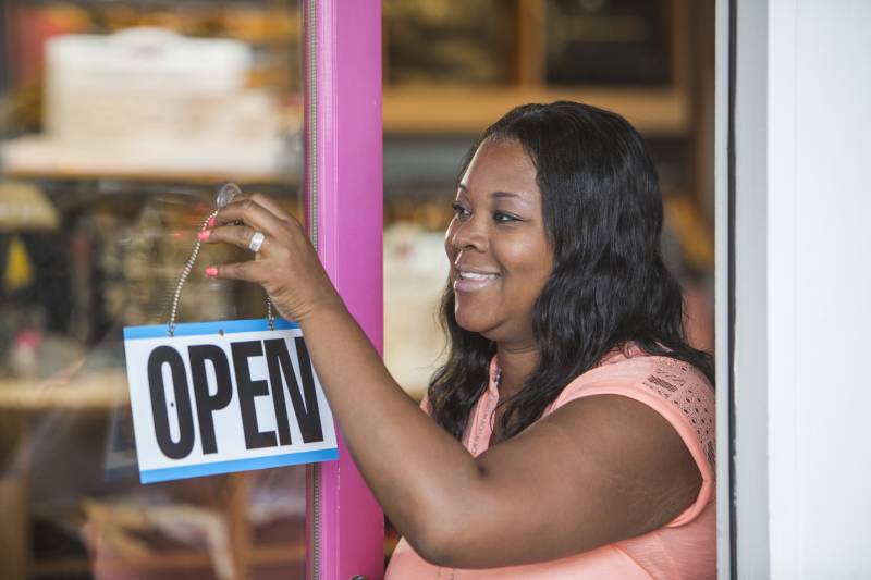 Small business owner changing sign on door to Open