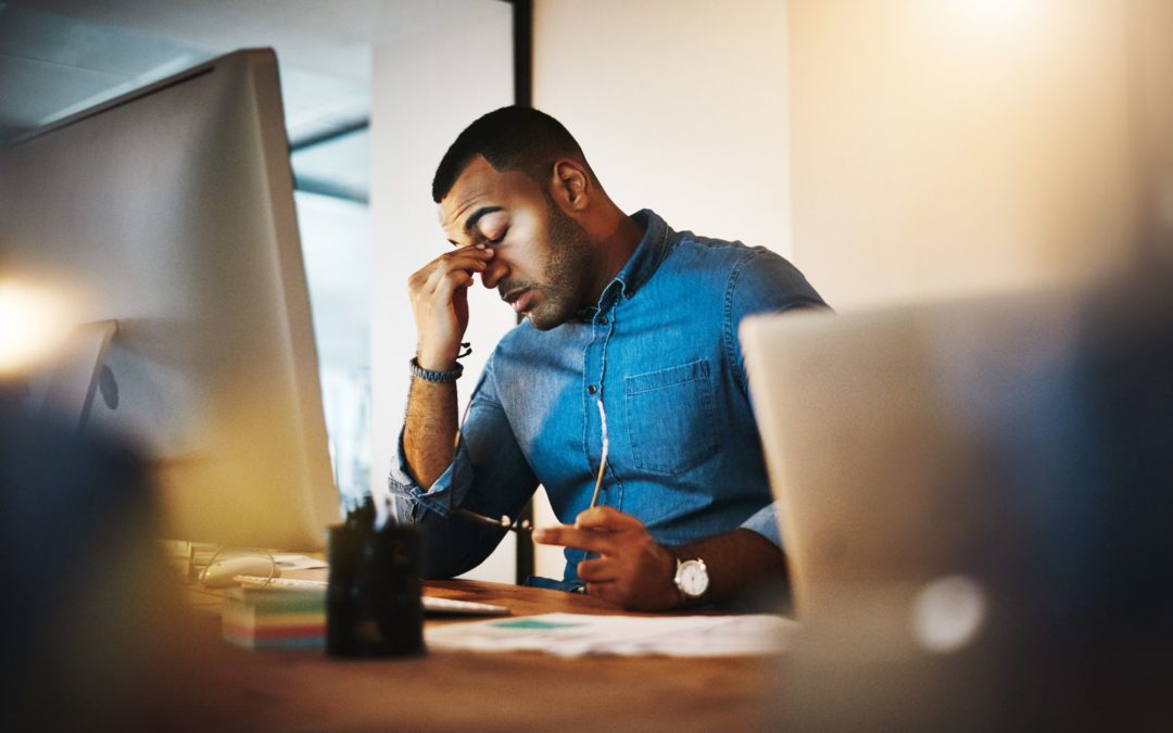 Hombre desempleado que parece estresado en el escritorio de su computadora