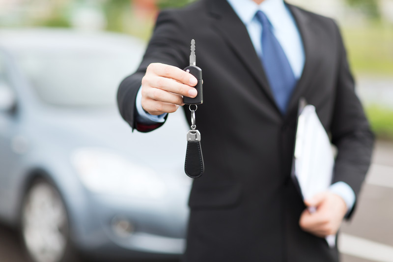 Agente de alquiler de coches entregándole las llaves de un coche de alquiler