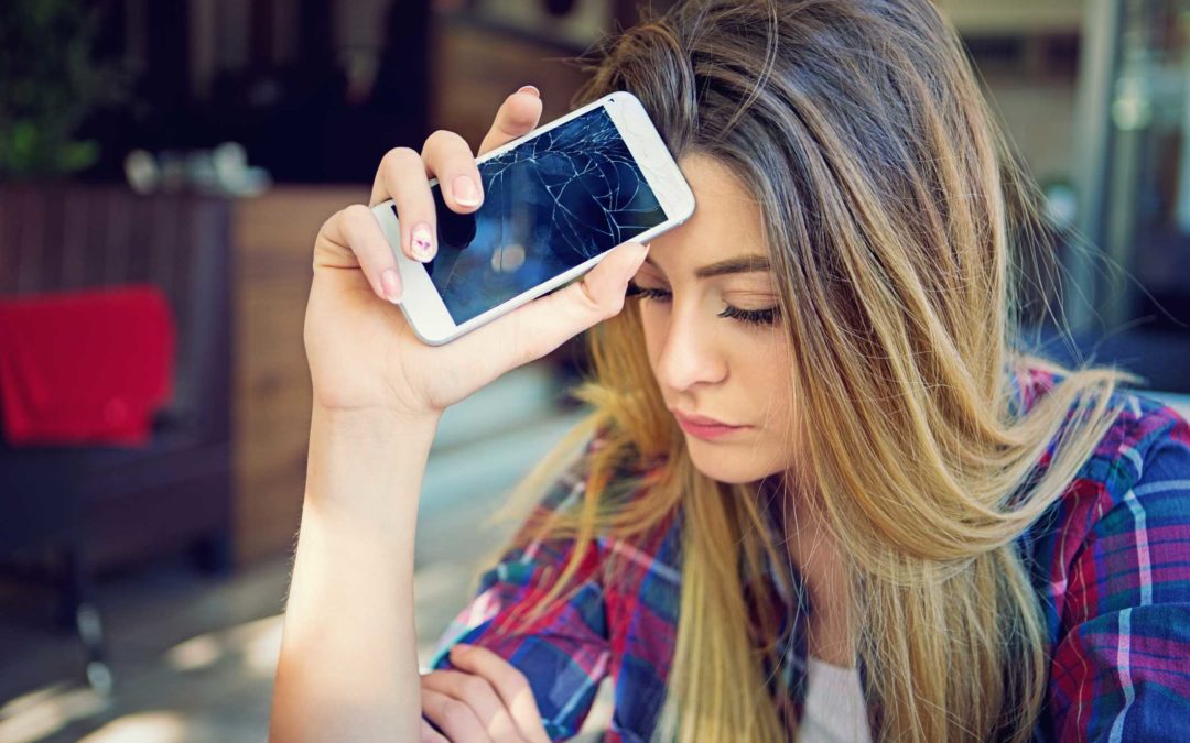 Adolescente angustiado sosteniendo un teléfono inteligente destrozado que no funciona