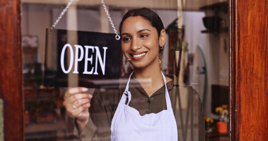 Small business owner changing the sign on your business to Open