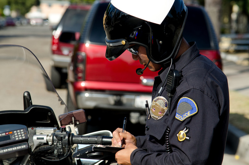 Policía de tránsito en motocicleta escribiendo una multa de tránsito
