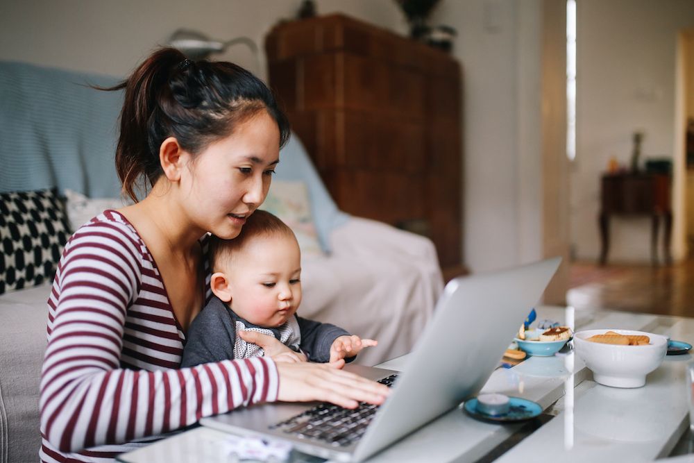 Young mother working from home with baby in her lap