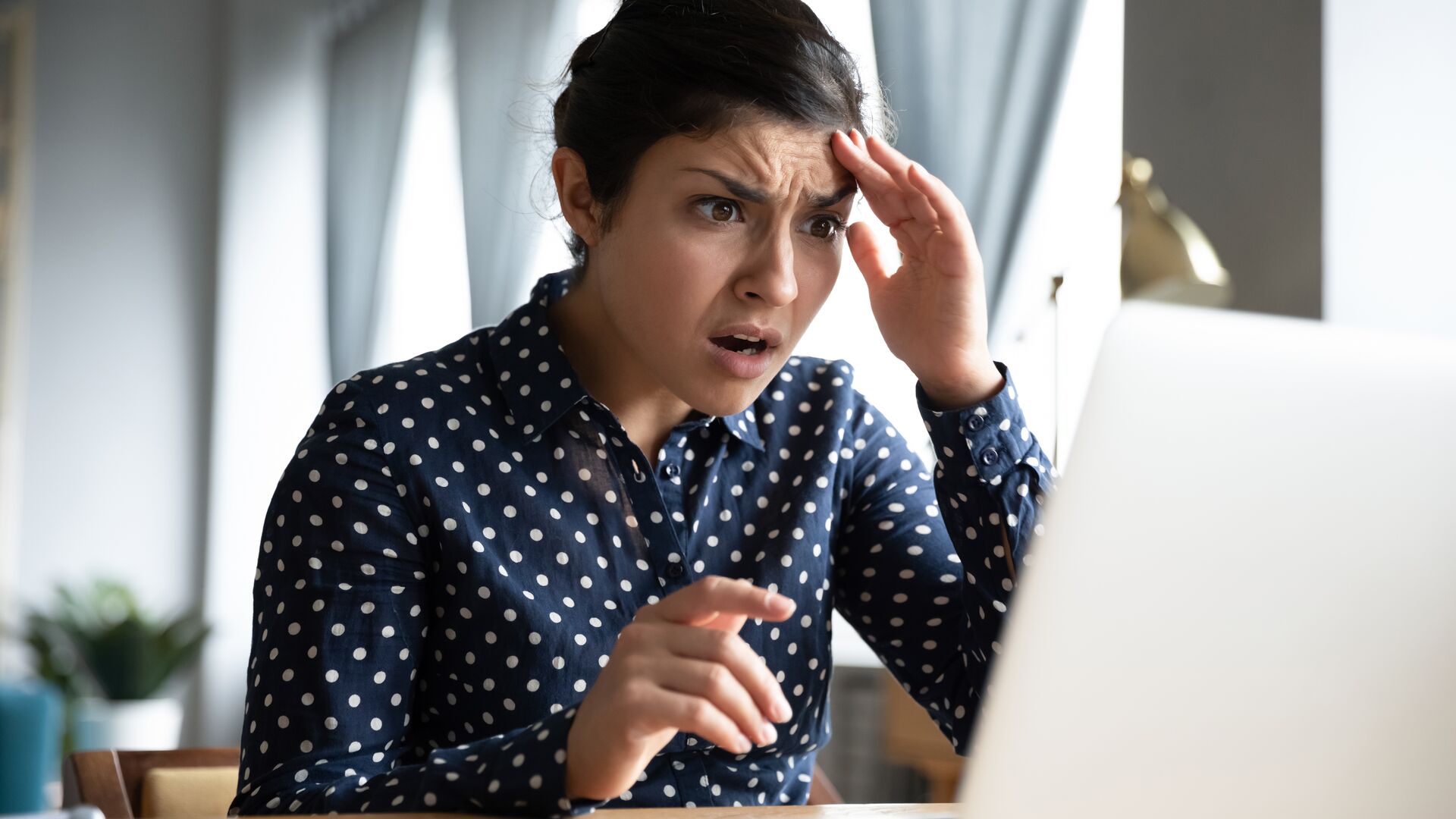Alarmed and worried woman looking at a laptop computer screen