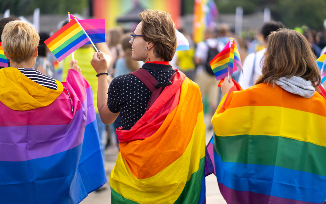 People wearing gay pride rainbow flags in street