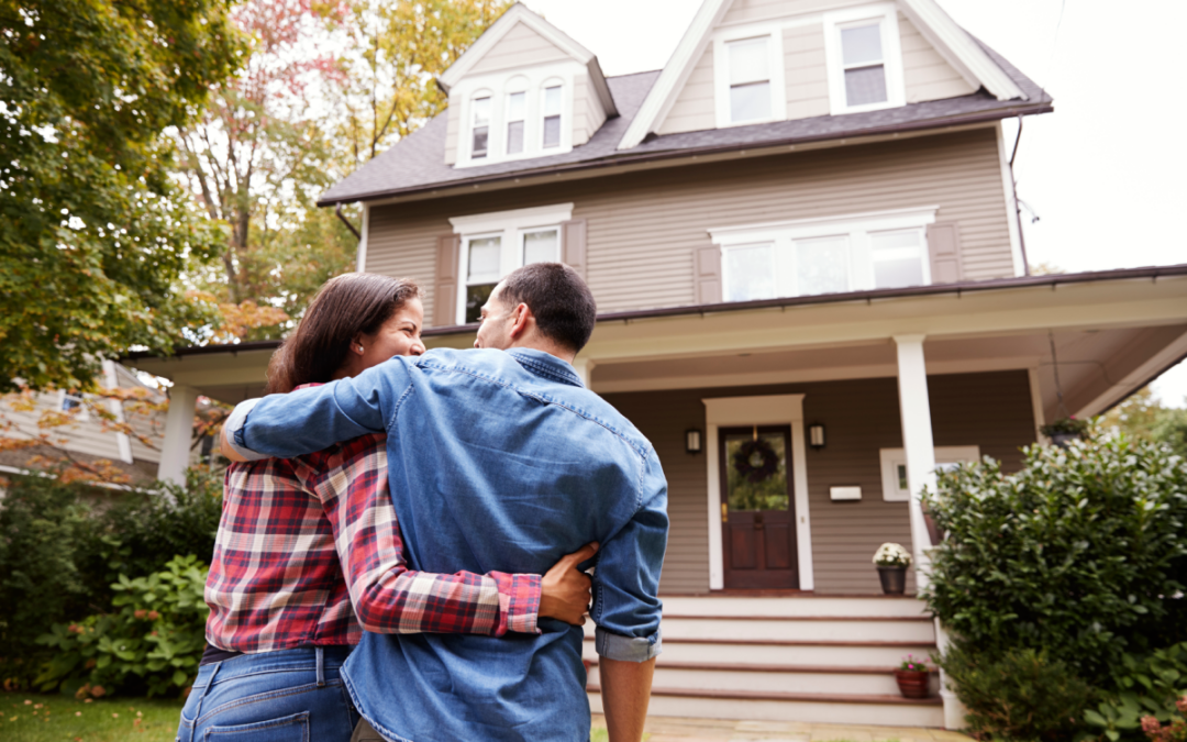 Homeowners in the front yard embracing and looking at their home