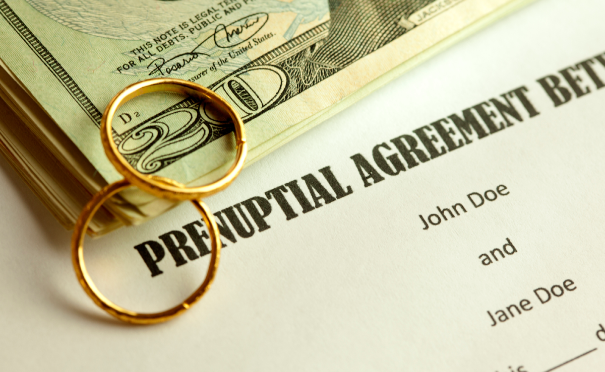 Prenuptial Agreement document with wedding rings & money 