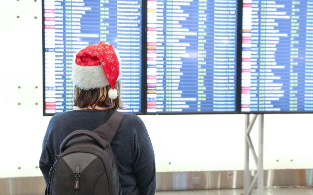 woman holiday traveler wearing Santa Claus hat looking at airport flight status board