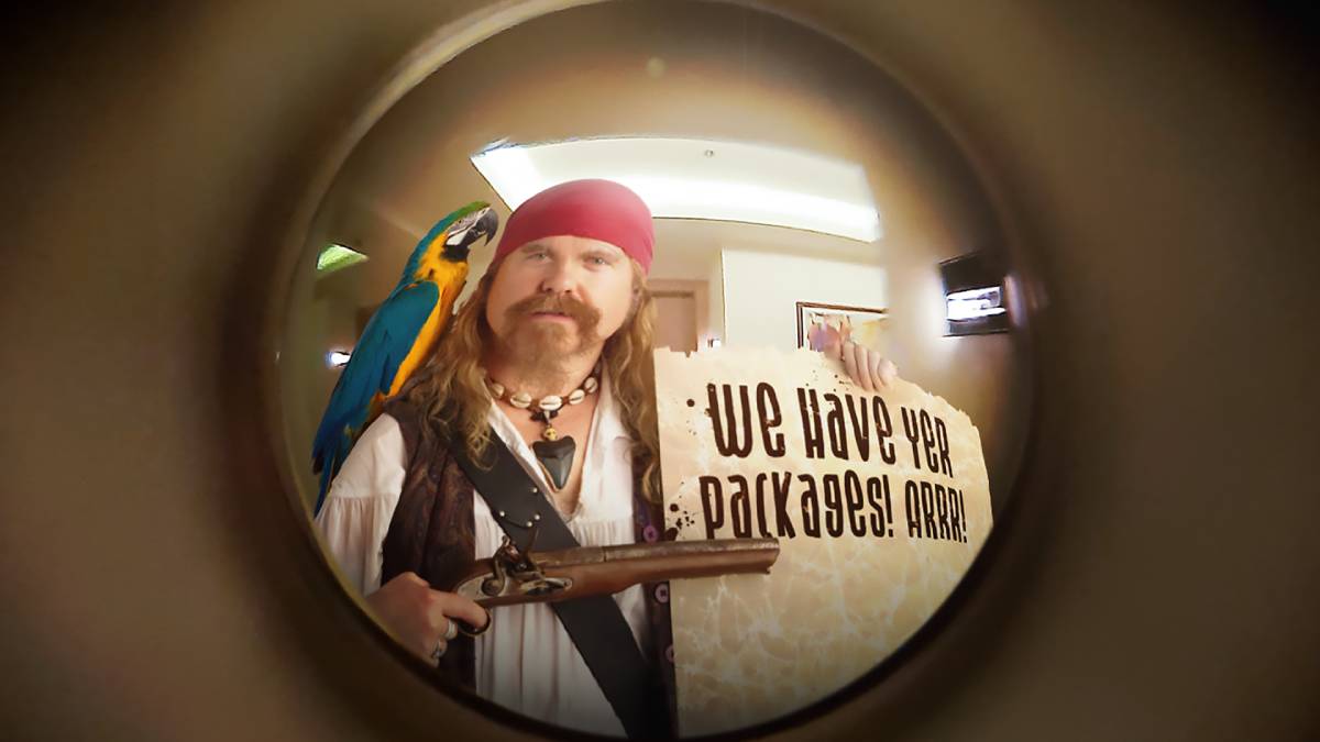 Hombre disfrazado de pirata de porche con un cartel que dice: ¡Tenemos sus paquetes! Arrr!