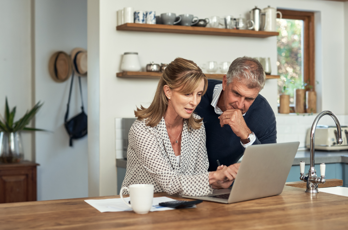 Una pareja consulta información sobre el impuesto de sucesiones en un portátil en su casa