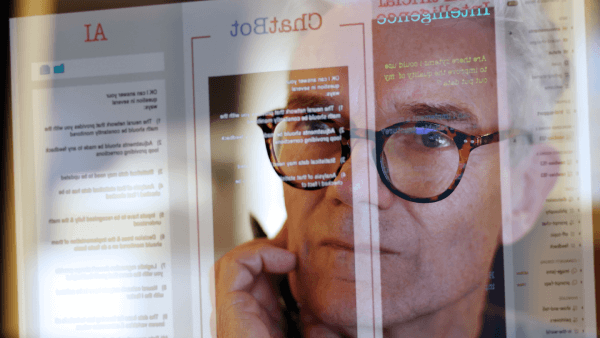 A lawyer's face is reflected on a computer monitor as he using an AI ChatBot to do legal work.