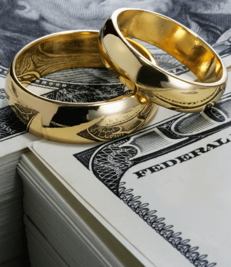 Gold wedding bands laying on paper money.