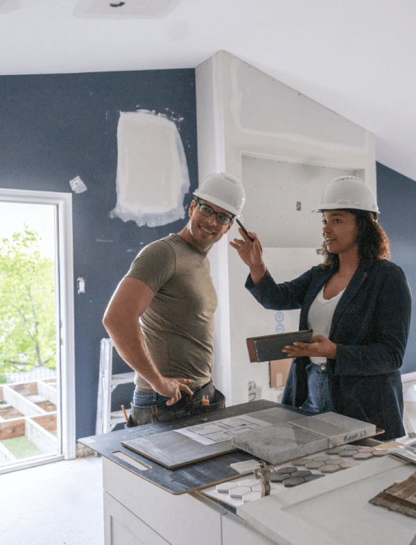 A woman house flipper instructing a construction worker on a house remodel.
