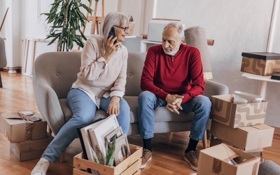 Mature couple in the process of moving. Woman is talking on a smartphone to inquire about moving insurance.