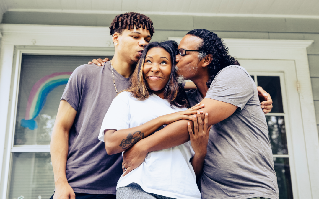 Father kissing his teen daughter as his teenage son stands nearby.