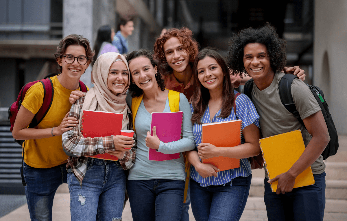A diverse group of teenage students holding notebooks.