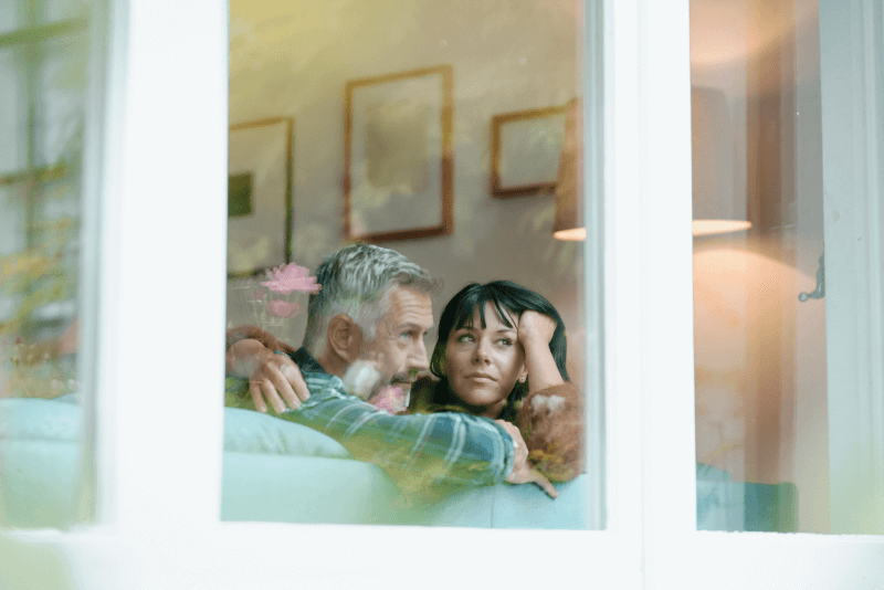 Middle-aged couple looking out picutre window.