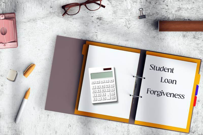 Cuaderno de notas, calculadora, bolígrafo y gafas sobre una mesa.