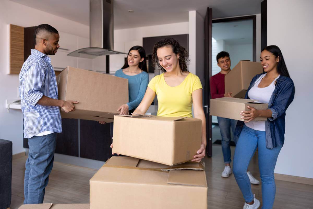 5 estudiantes universitarios trasladan cajas a su apartamento alquilado.