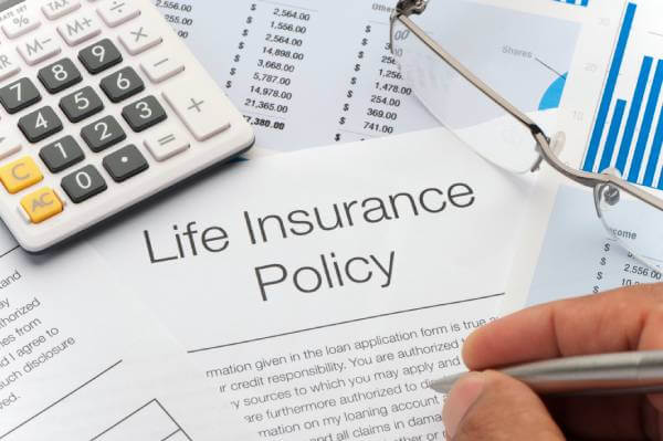 A Life Insurance Policy by a calculator and other estate planning documents.