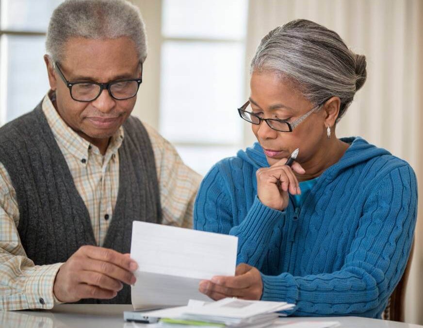 An older man and woman reviewing a car repossession notice in their home.